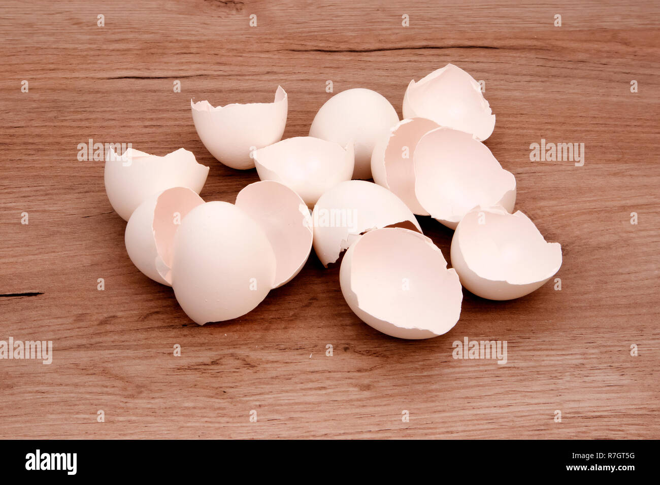 A pile of empty white egg shells lying on a wooden board surface Stock Photo