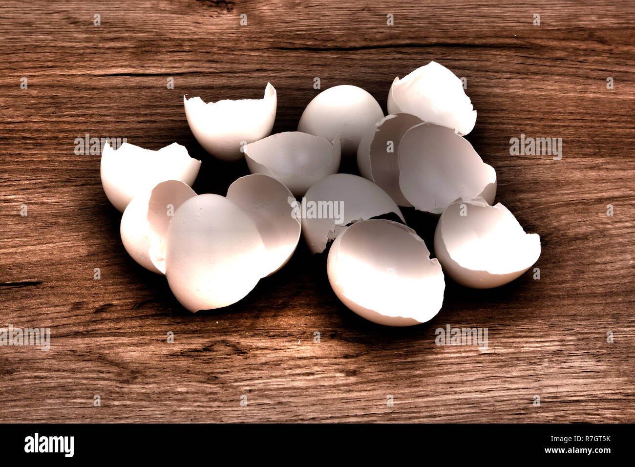 A pile of empty  white egg shells lying on a wooden board surface, HDR toning image with shadows Stock Photo