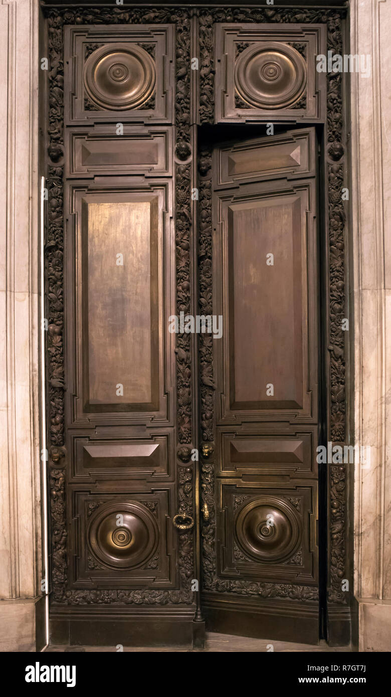 Antique wooden massive half opened door with carved wooden ornament and copper knob Stock Photo