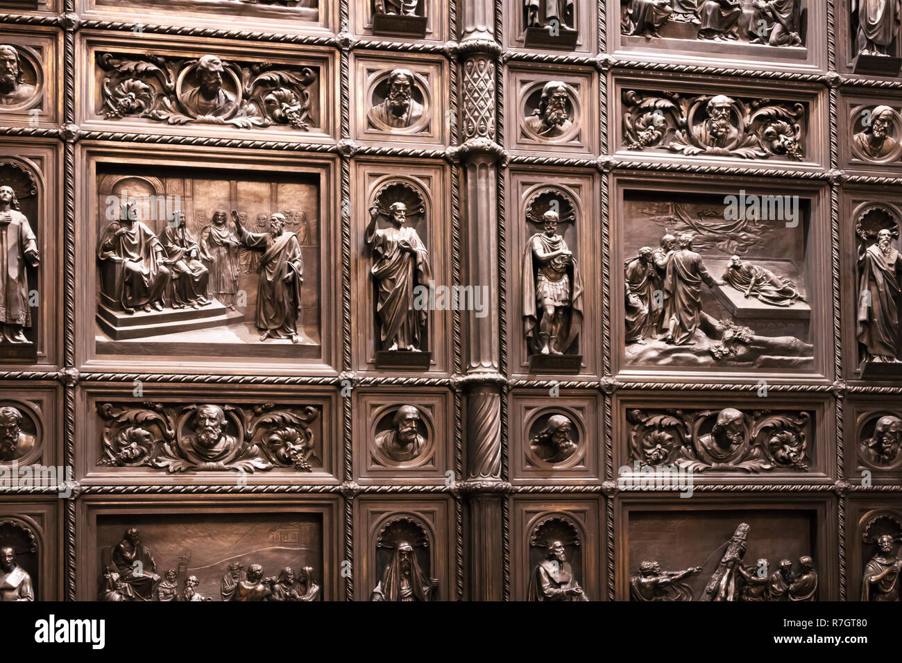 Antique wooden massive door leaf with carved wooden figures placed in cells Stock Photo