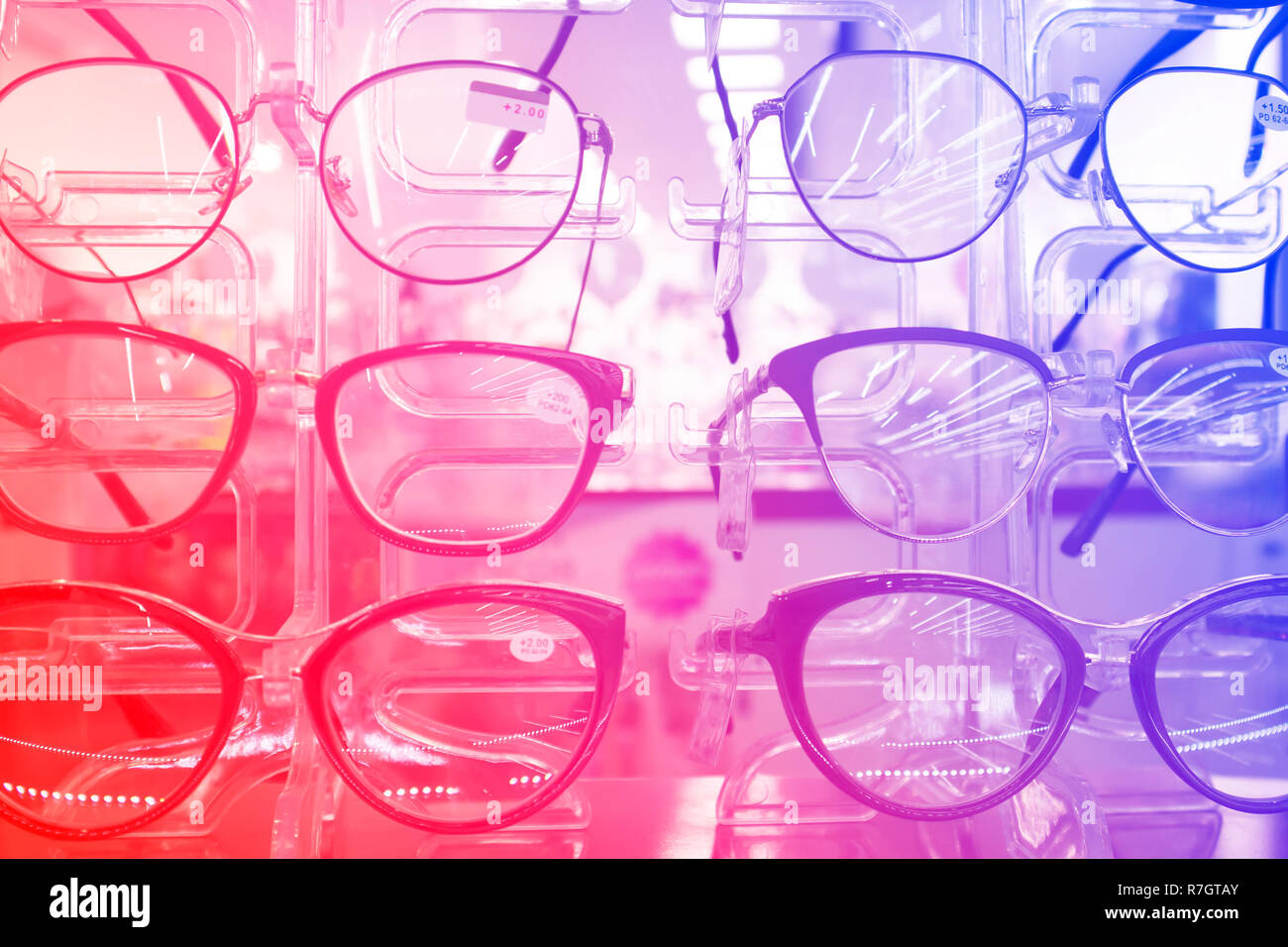 The rack with fashion eyeglasses in the optic store, decorated with red-blue gradient Stock Photo