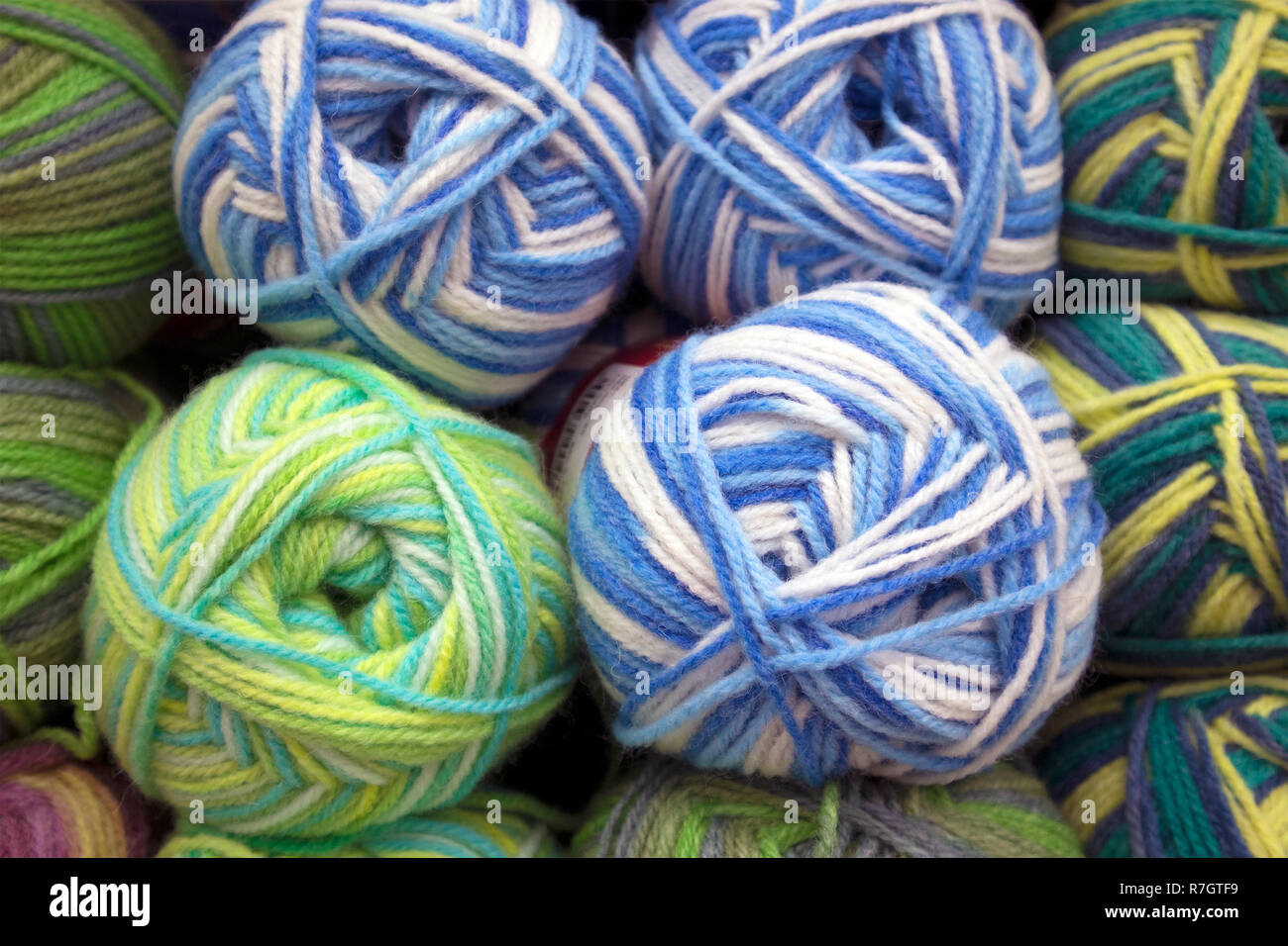 A number of multicolored woolen skeins arranged in rows on a store shelf, yarn texture Stock Photo