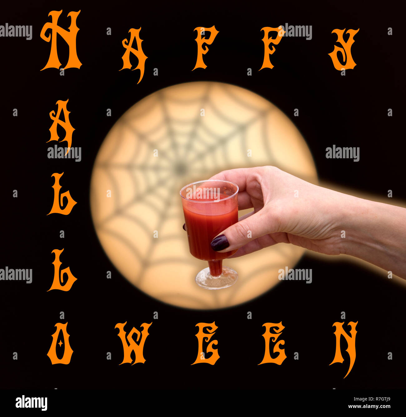 Halloween greeting card or banner, woman hand with glass of red liquid against moony circle and spider web Stock Photo