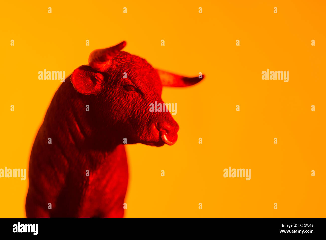 Toy bull against orange-yellow glowing sunset type backdrop. Metaphor for 'confidence' and Stock Market bulls, bullishness. See ADD. DETAILS NOTE Stock Photo