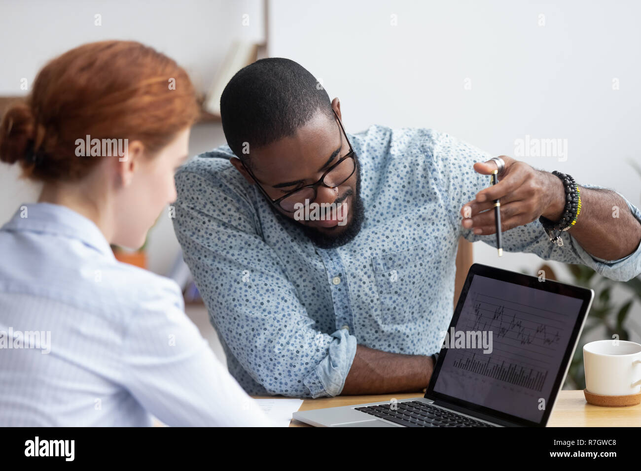 Colleagues working together analyzing data looking at laptop scr Stock Photo