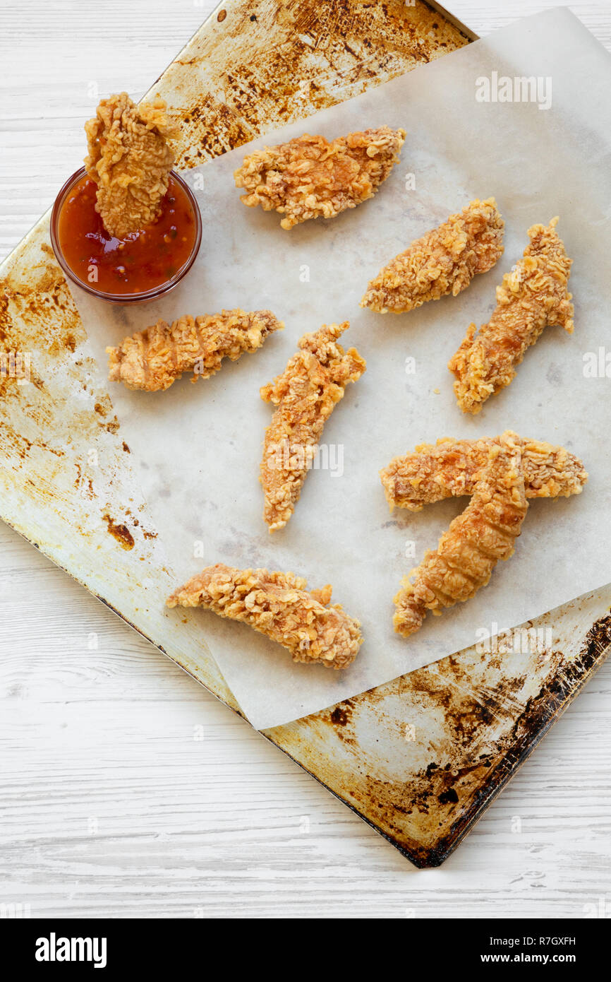Chicken strips and sauce on baking tray, top view. Overhead, from above