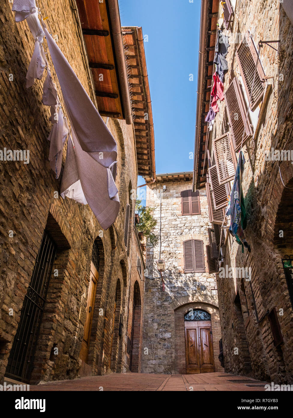Refreshing and mediterranean atmosphere in narrow street with drying clothes on clothesline on a summer morning, Tuscany, Italy Stock Photo