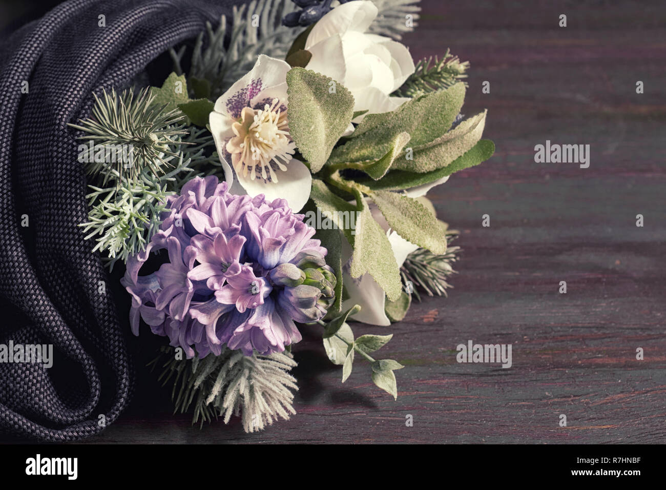 Winter decor. Flower bouquet in the winter style with blue hyacinth, white anemones and branches of christmas tree on dark wood covered with dark fabr Stock Photo