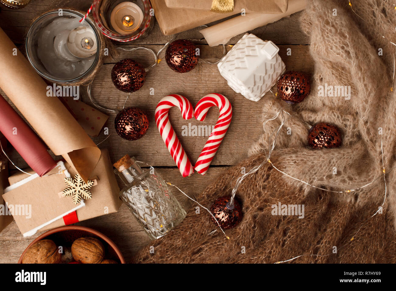 Christmas mood still life on a wooden background with heart-shaped candy cane, Happy holidays gift box, candles and lights, xmas background, instagram Stock Photo