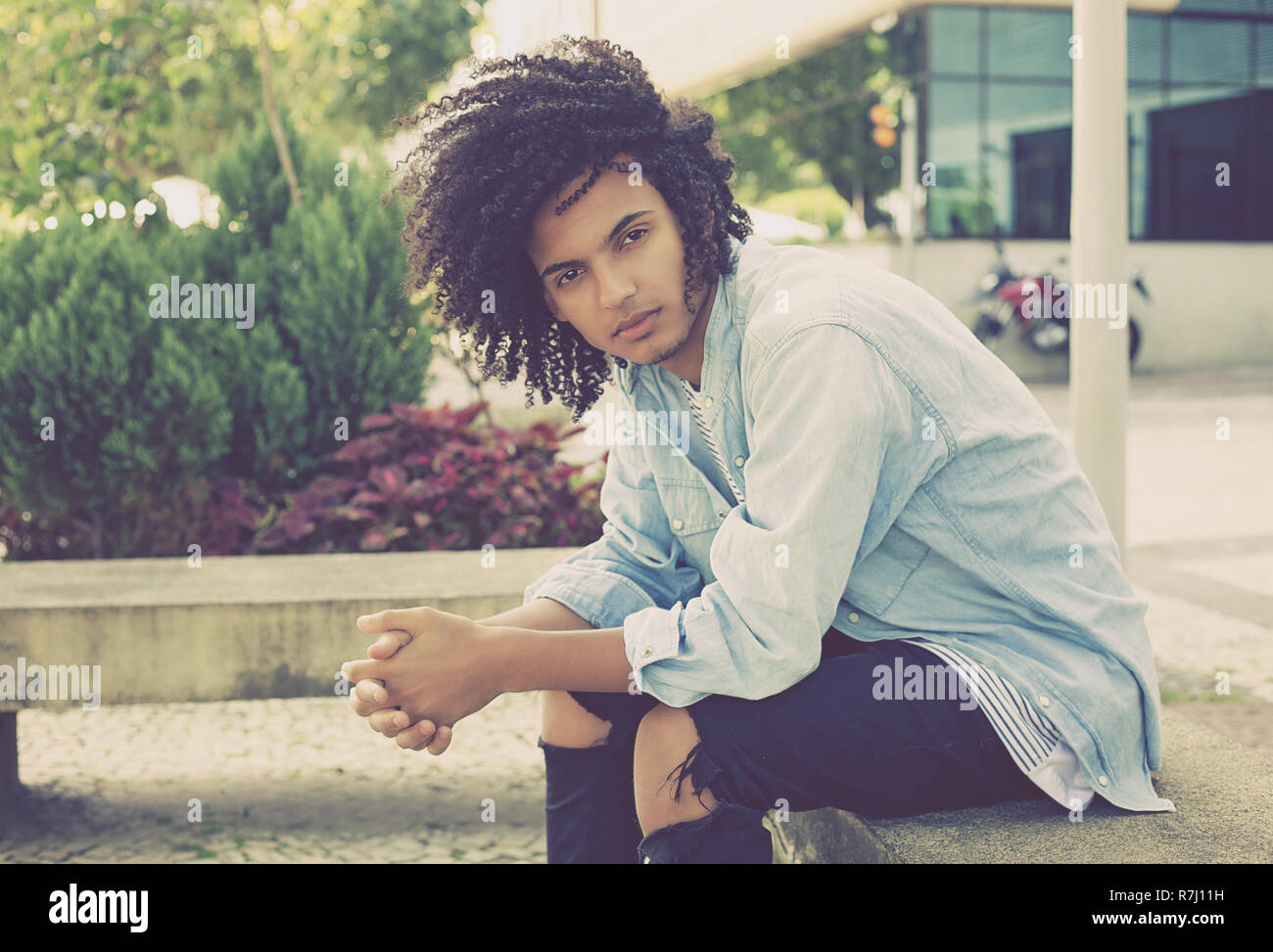 Fashionable young adult man with long curly hair outdoor in the city Stock Photo