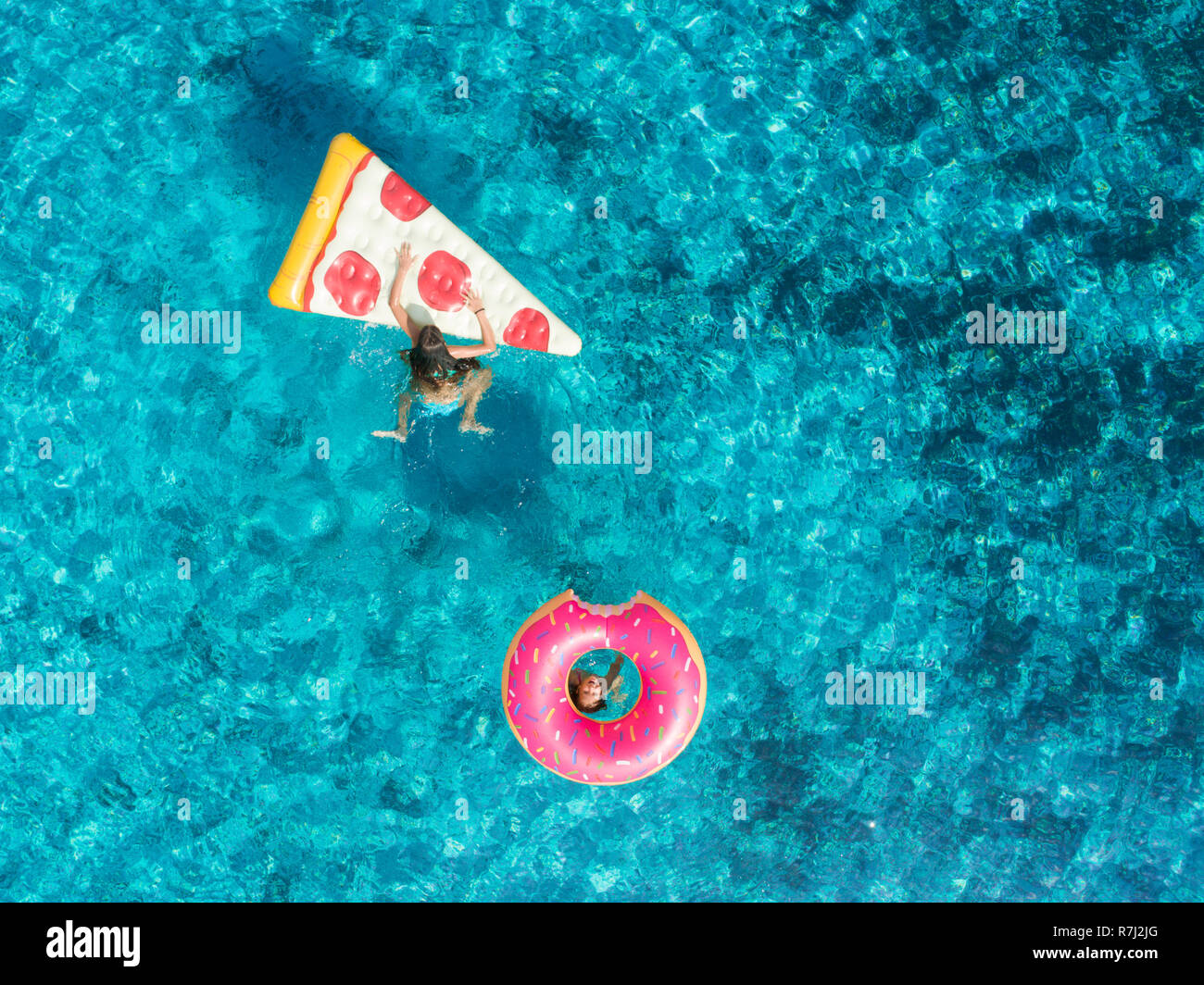 Aerial view of two young girls swimming and playing in sea with ...