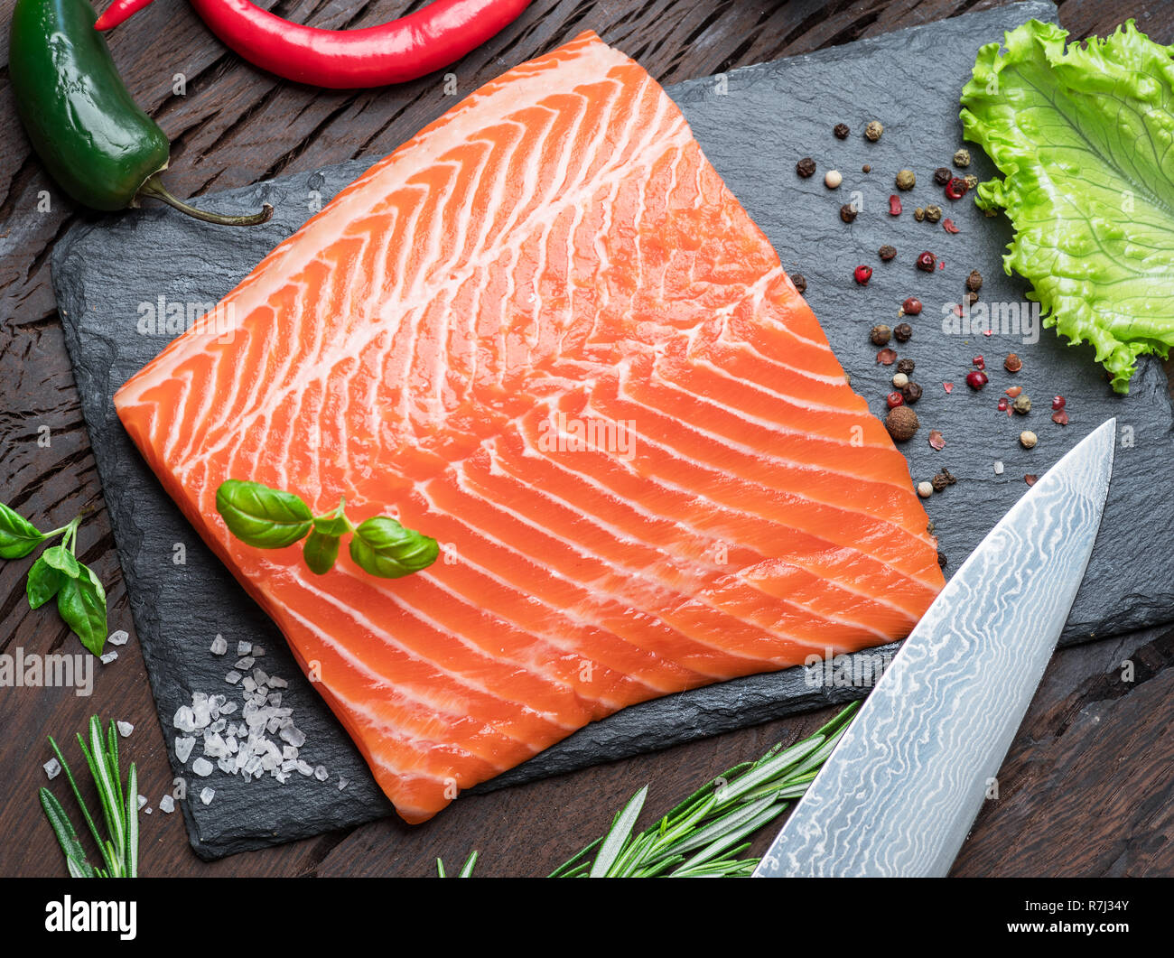 Fresh salmon fillet on black cutting board with herbs and spices. Top ...