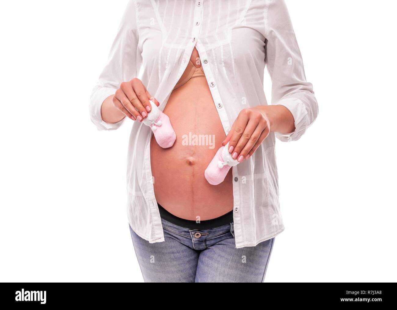 Pregnant woman holding baby socks on her stomach. Stock Photo