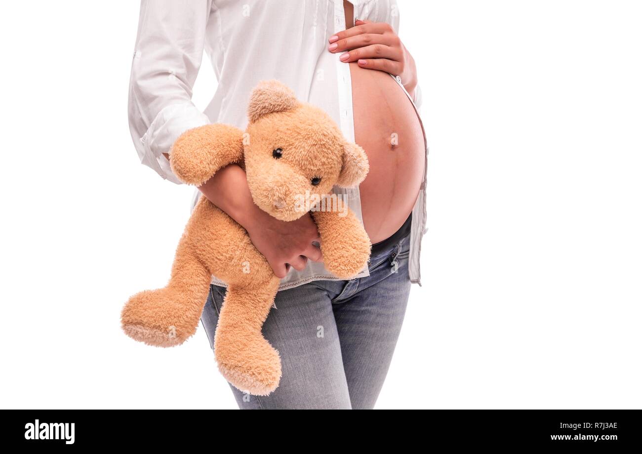 Pregnant woman is holding a bear near the belly. Stock Photo