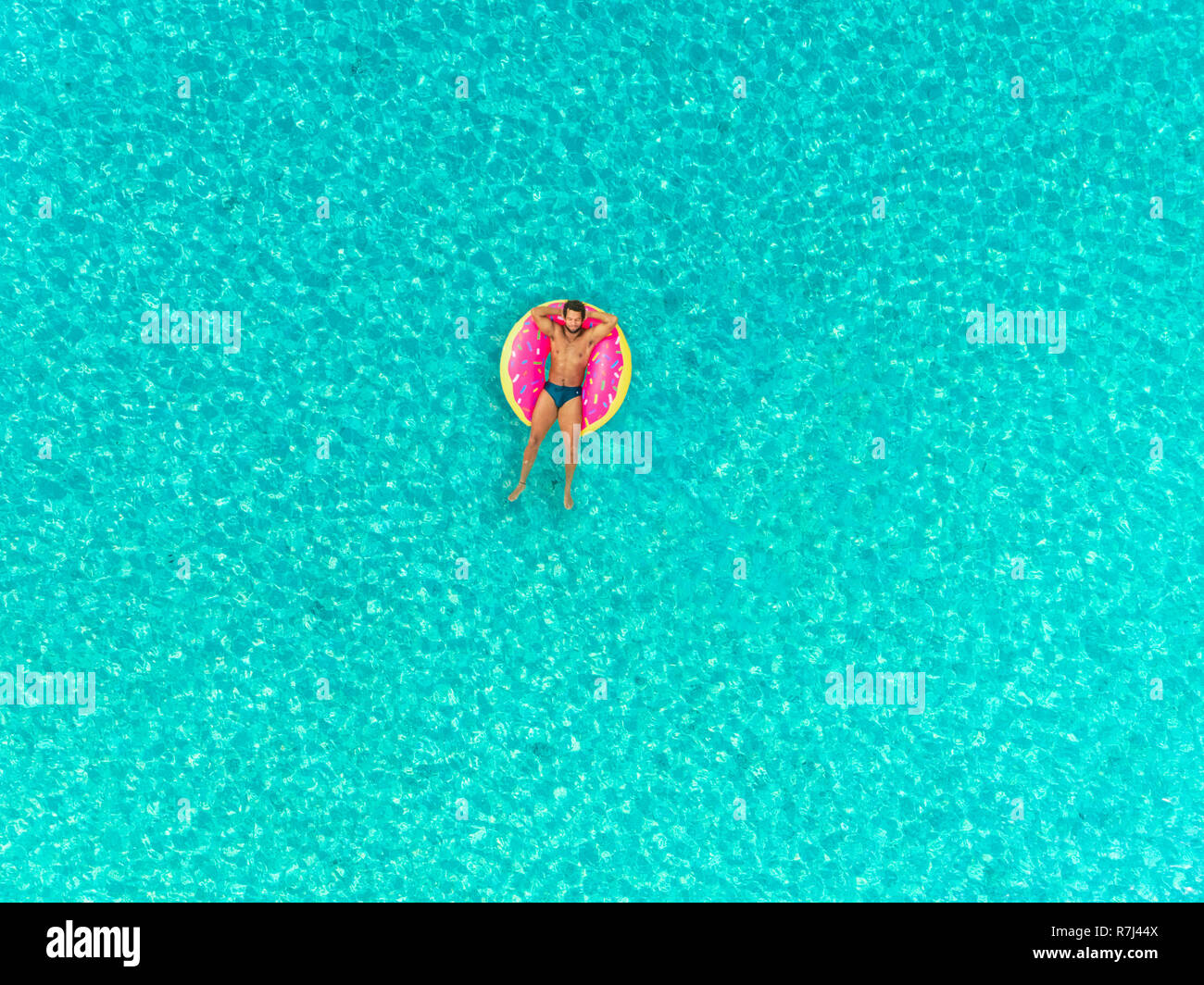 Aerial view of man floating on inflatable donut mattress, relaxing. Stock Photo