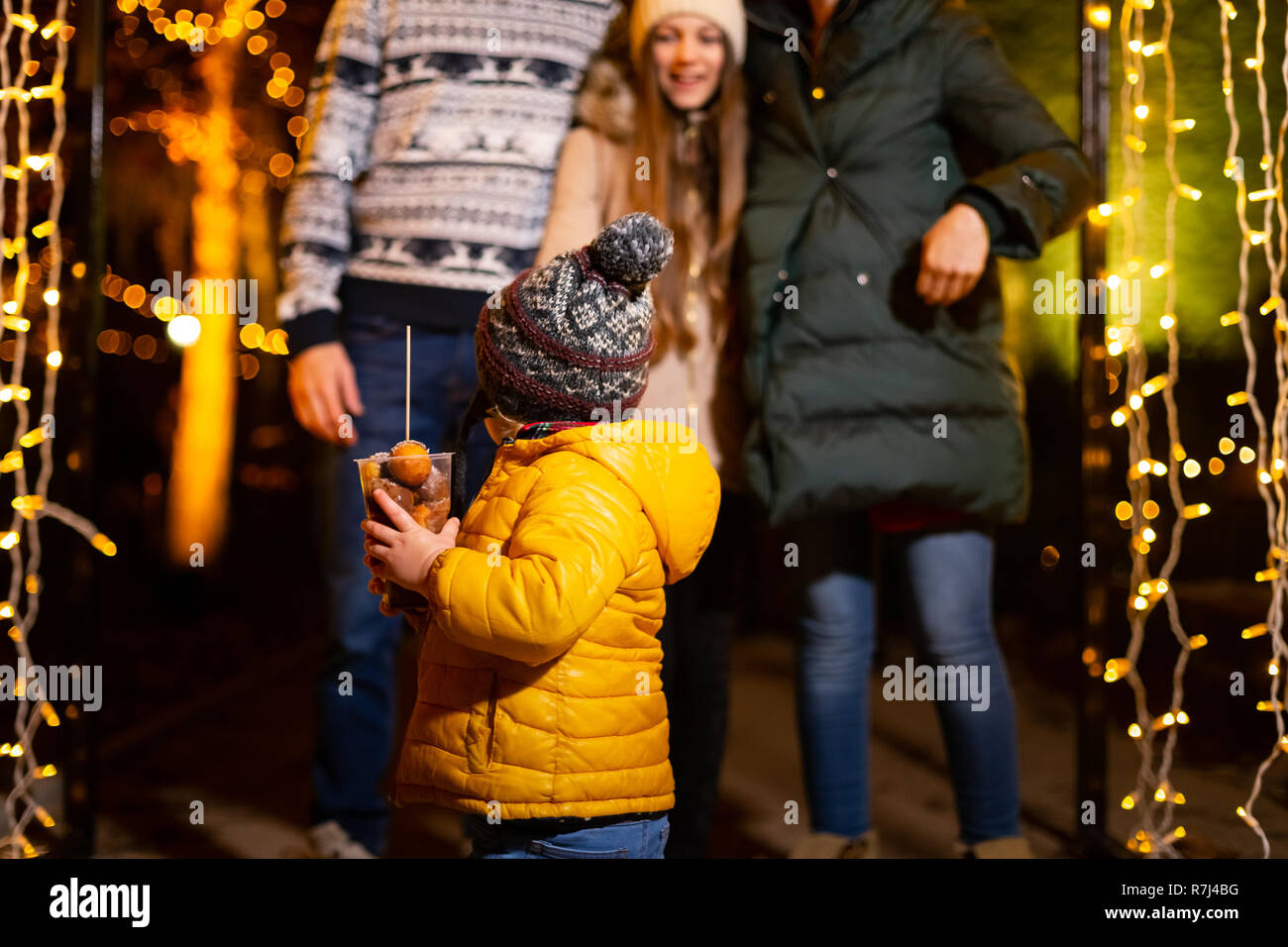 Young boy holding traditional food in frot of family at Christmas market, Zagreb, Croacia. Stock Photo