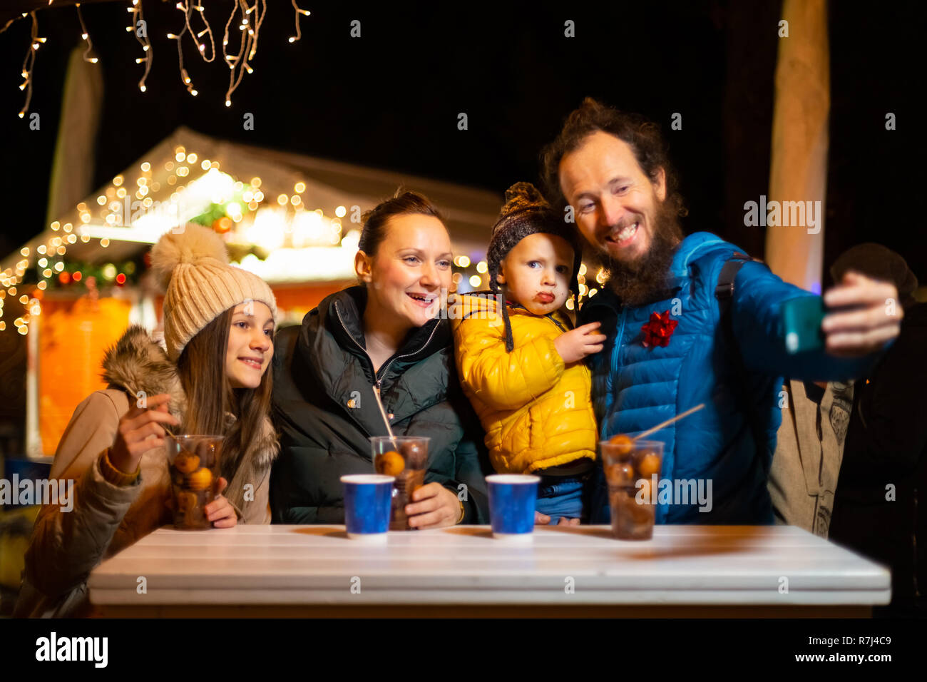 Father taking selfie with family at traditional Christmas market in Zagreb, Croatia. Stock Photo