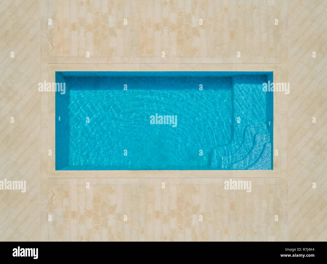 Aerial abstract view of empty swimming pool with tiled area. Stock Photo