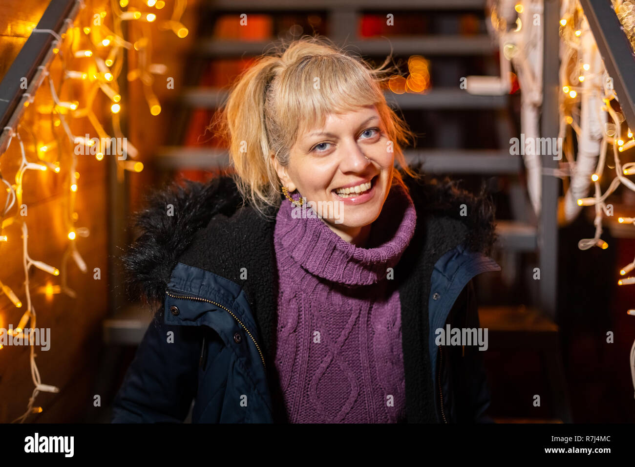 Portrait of happy woman sitting on stairs at Christmas market. Zagreb, Croatia. Stock Photo
