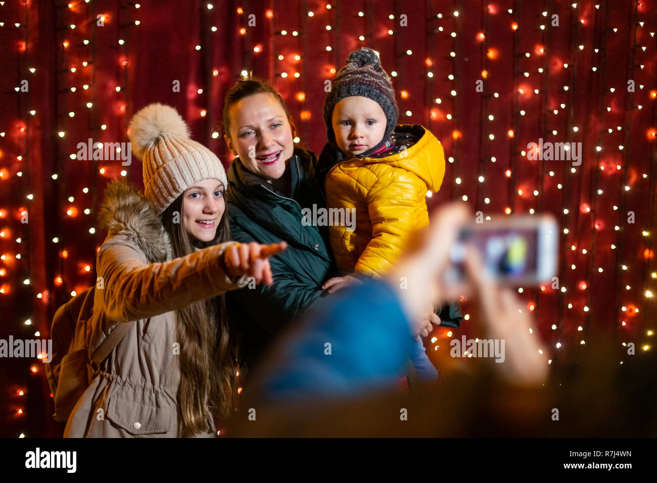 Father taking photo of family at Christmas market on the night. Stock Photo