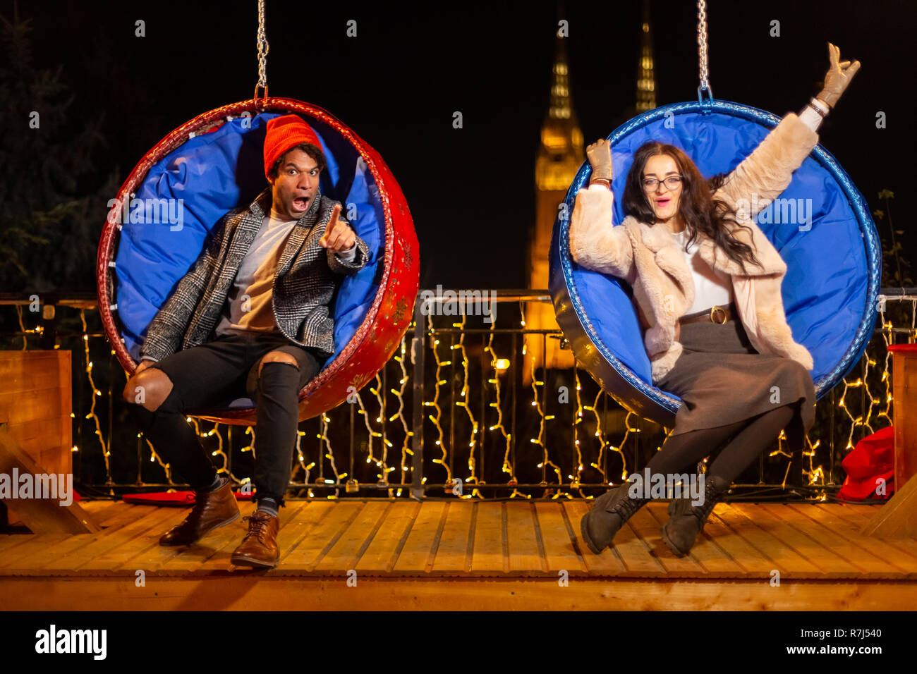Couple having fun on hanging Christmas chairs, Zagreb, Croatia. Stock Photo