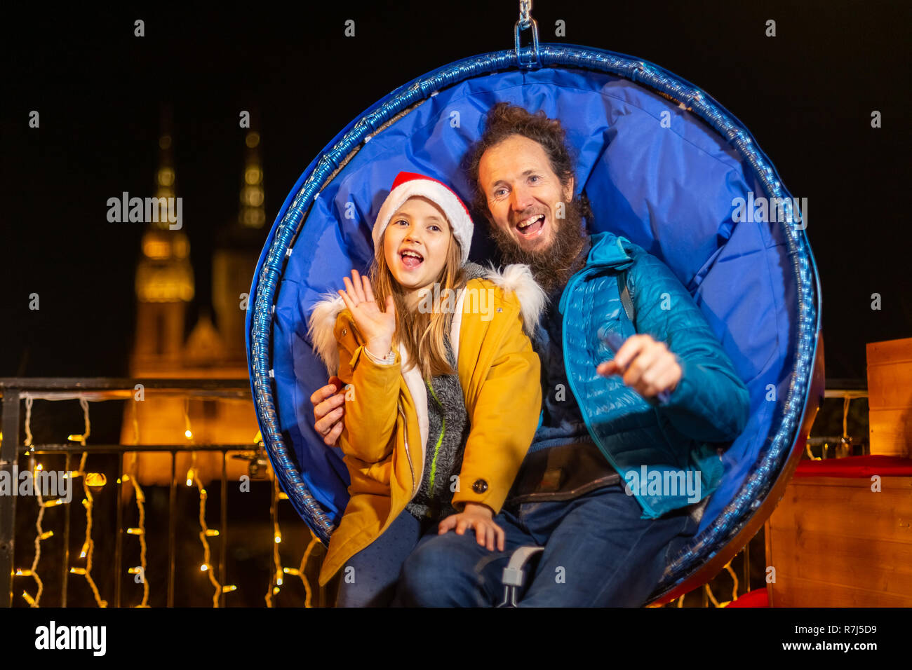 Father and daughter seated on hanging Christmas chairs, Zagreb, Croatia. Stock Photo