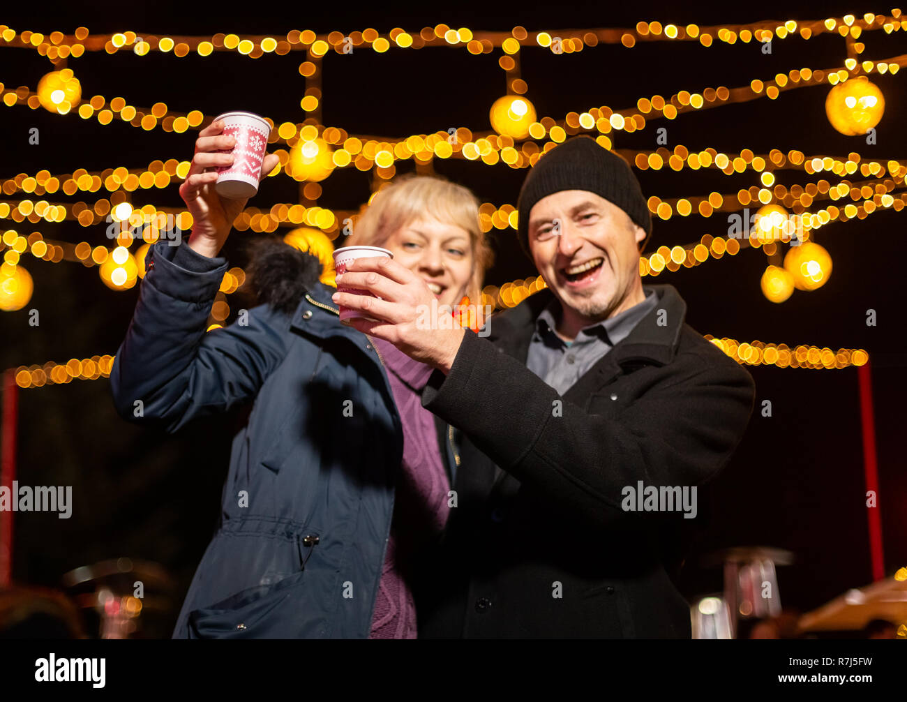 Couple cheering towards camera at Christmas market. Zagreb, Croatia. Stock Photo