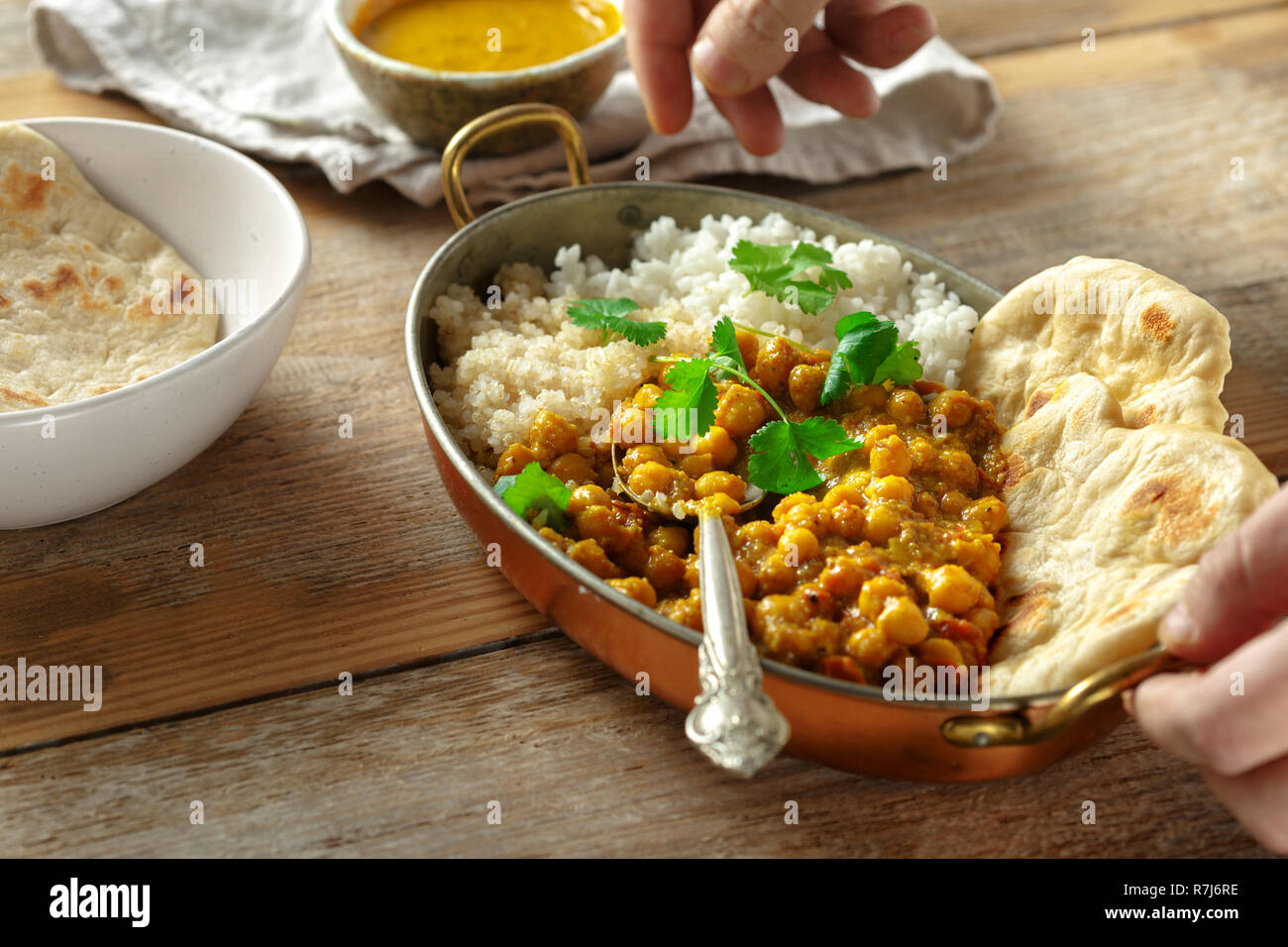 Chickpea curry, rice and quinoa in pan on wooden table. Tasty and healthy Asian lunch. Asian food concept Stock Photo