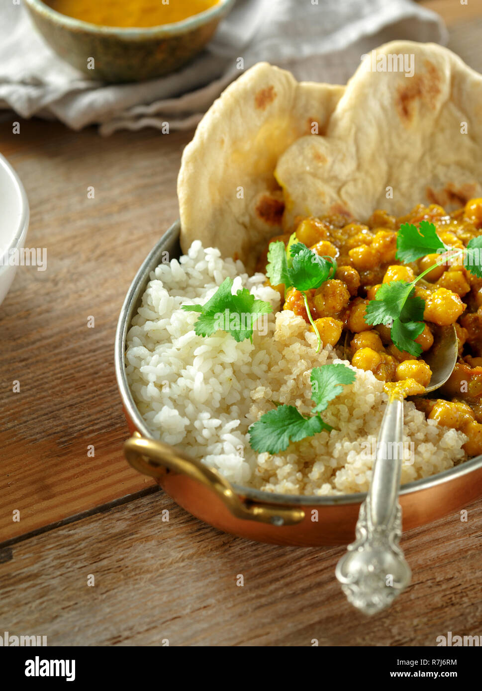 Chickpea curry, rice and quinoa in pan on wooden table. Tasty and healthy Asian lunch. Asian food concept Stock Photo