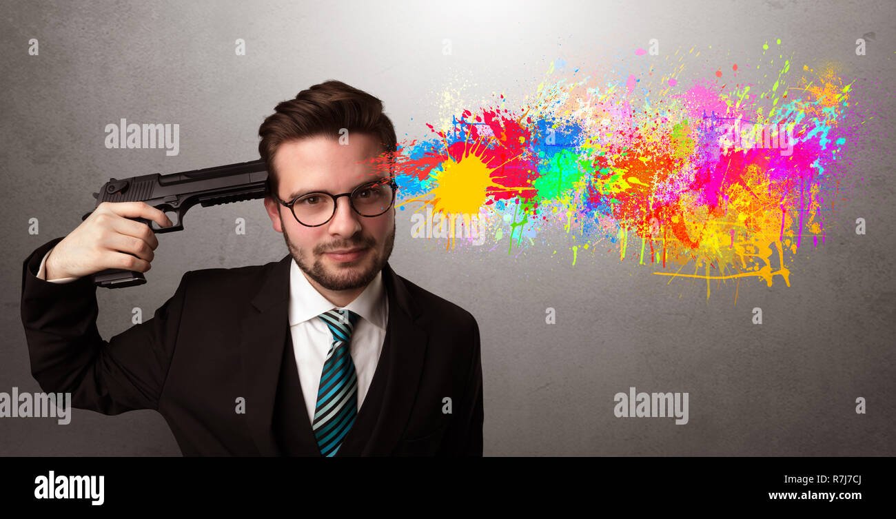 Man shoots his head with gun and colorful splotch are coming out from his head Stock Photo