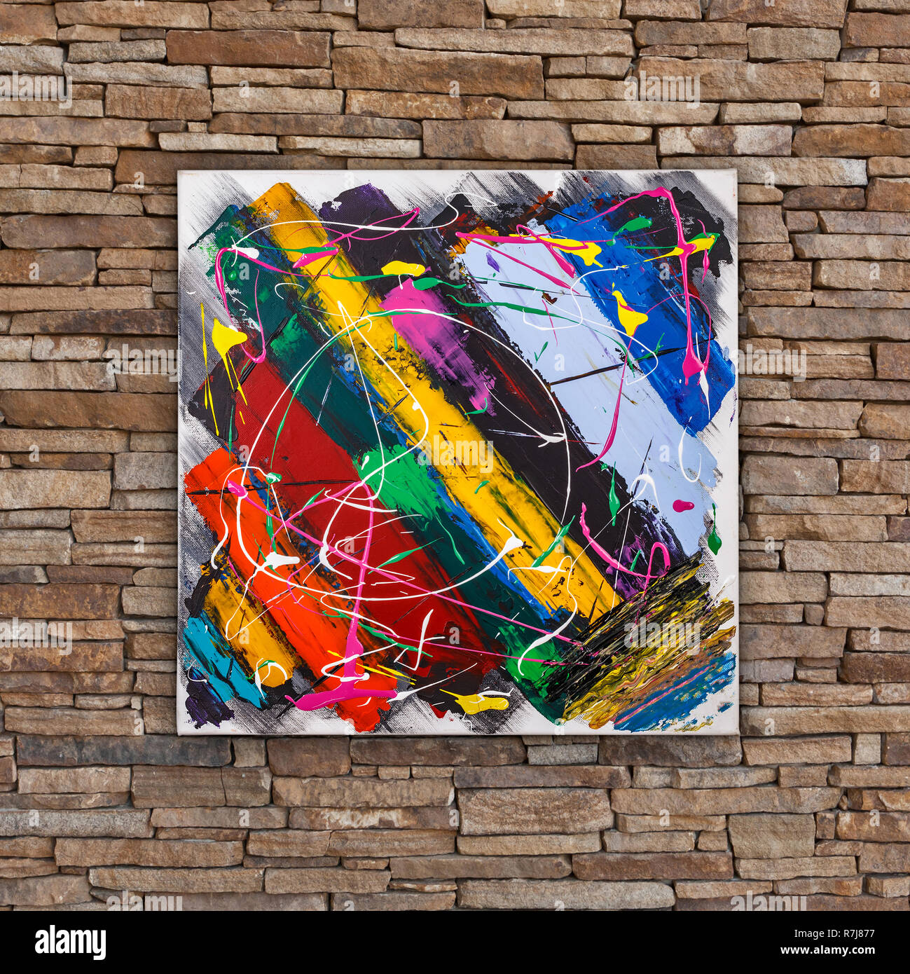 Abstract colorful oil painting, brush stripes and splashes, painted by Attila Hajnal, hanging on stone wall Stock Photo