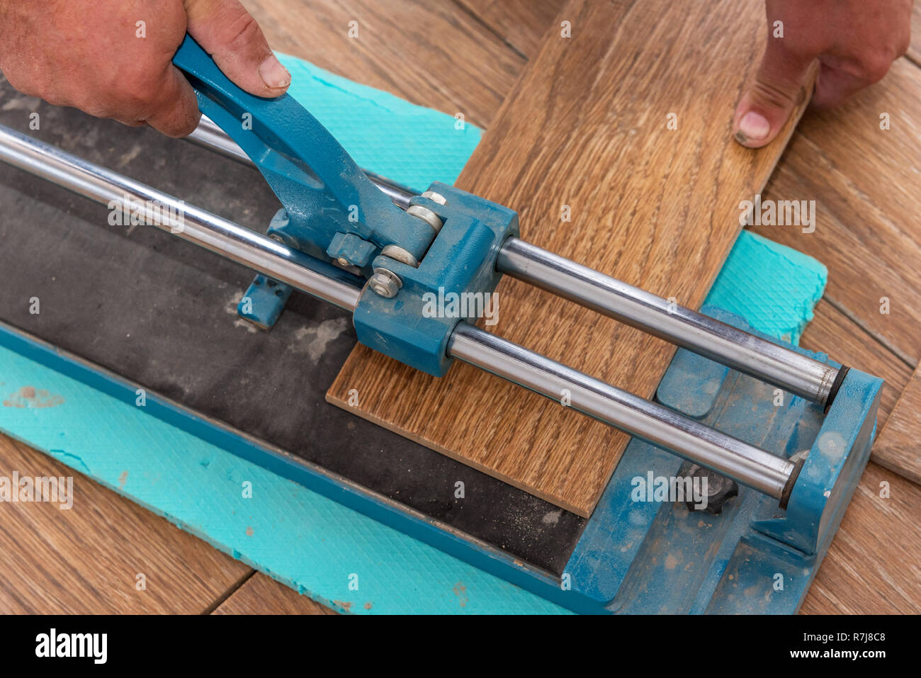 The man is cutting the floor tiles using a tile cutter machine Stock Photo  - Alamy