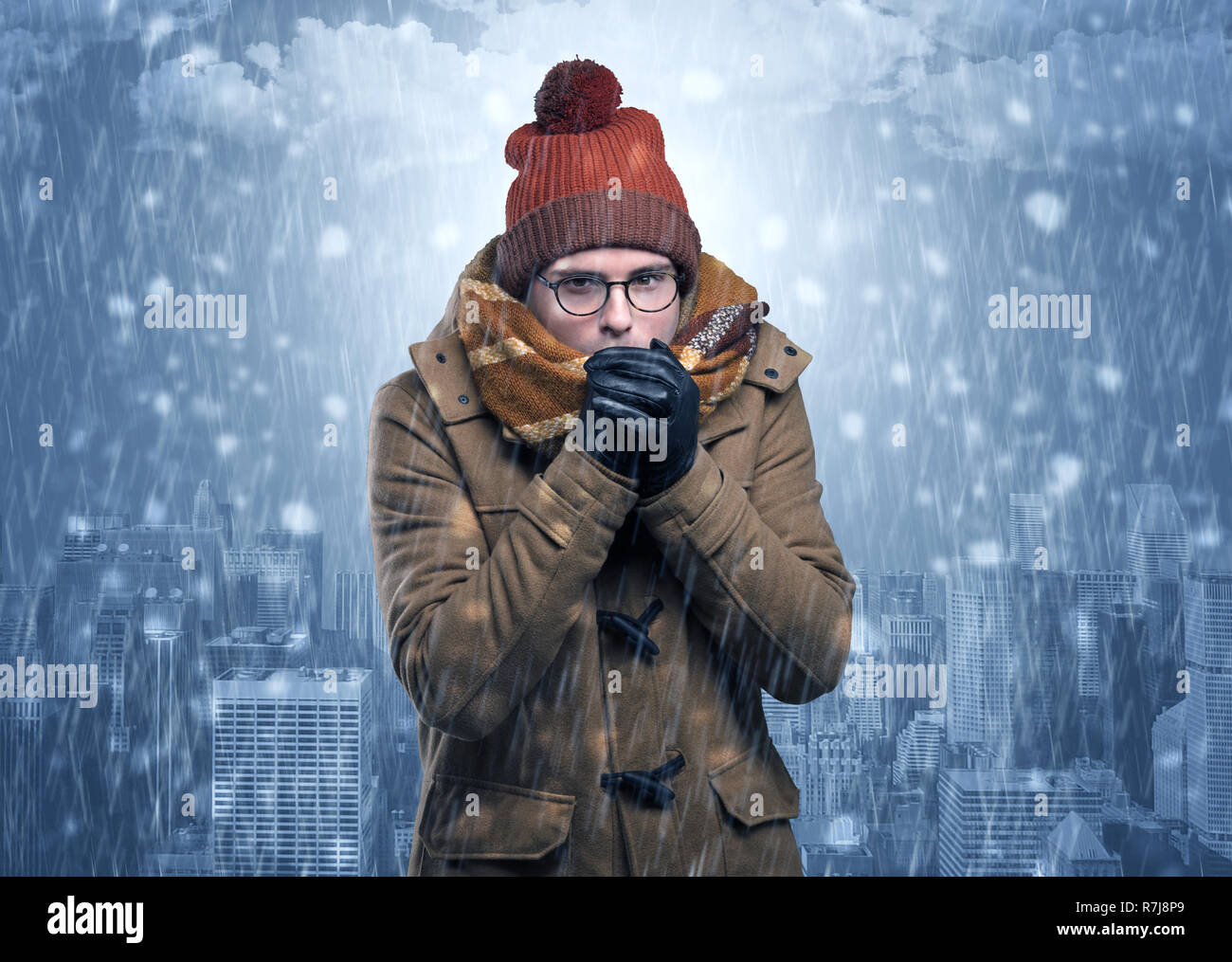 Young man freezing in warm clothing with city concept  Stock Photo