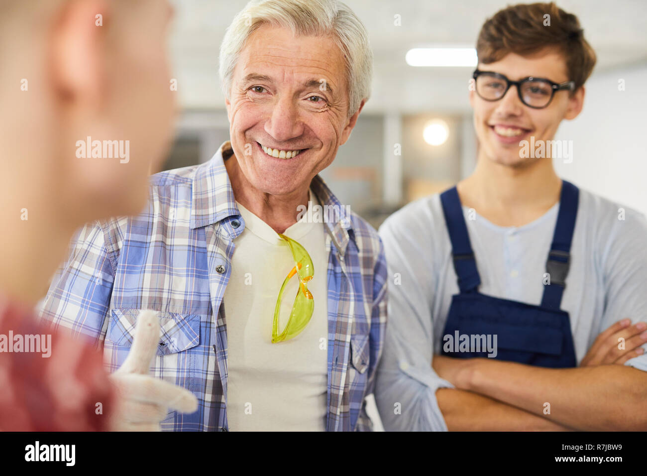 Smiling carpenter teaching young students at woodworking class Stock