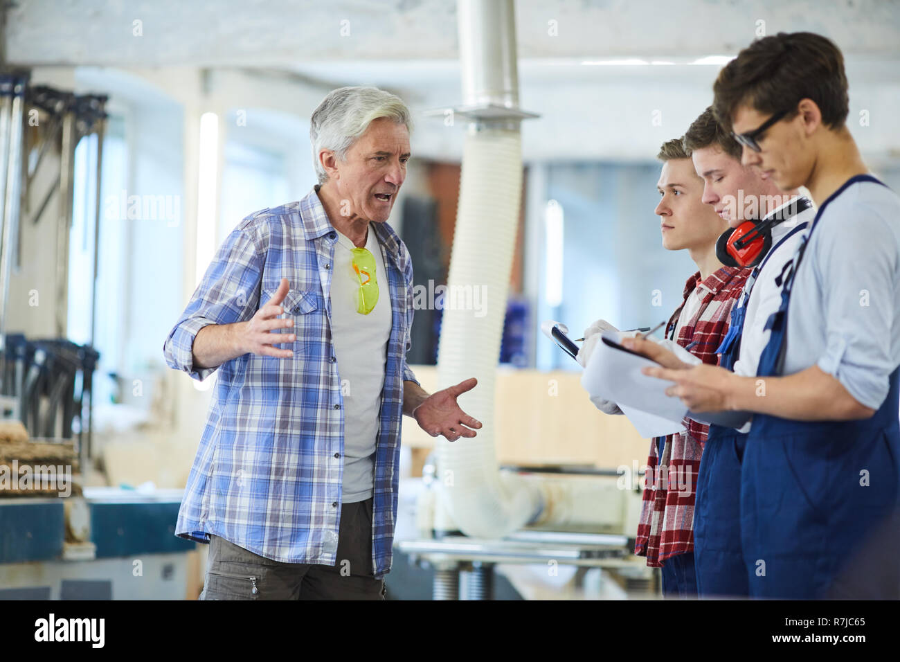Annoyed carpenter dressing down young workers Stock Photo