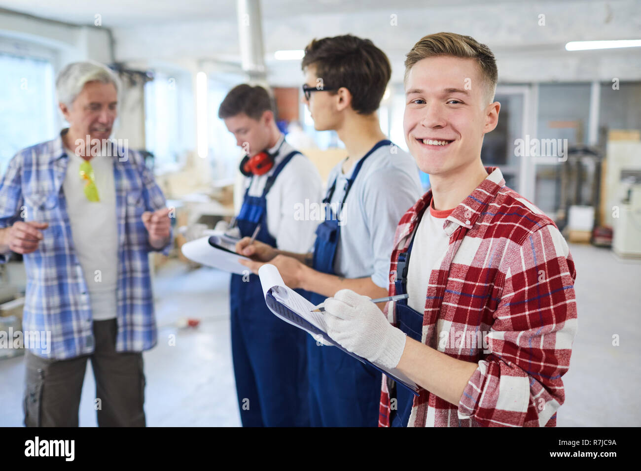 Content young carpentry worker making notes in clipboard Stock Photo
