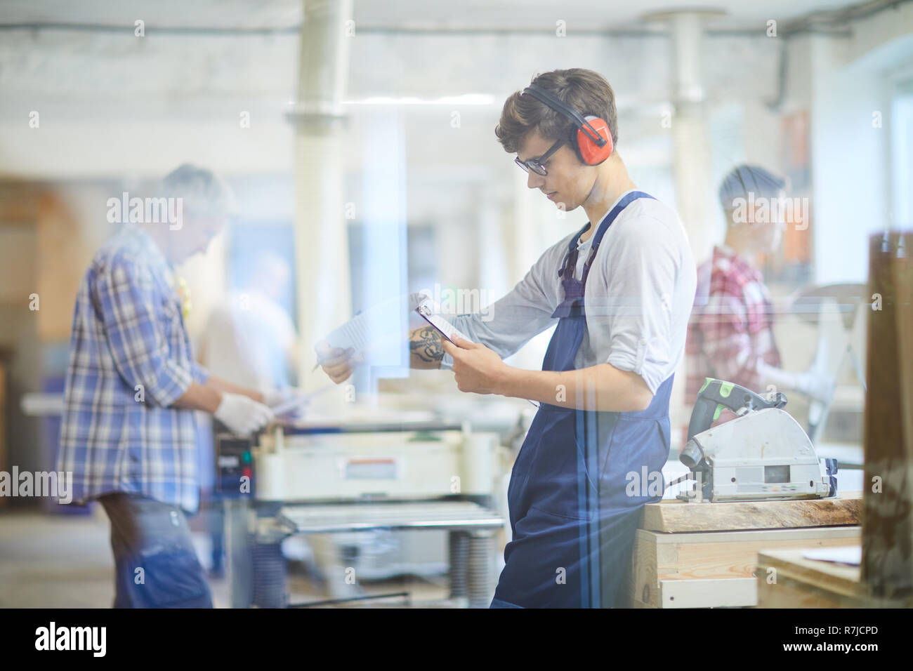 Busy young joiner reading operation manual in workshop Stock Photo