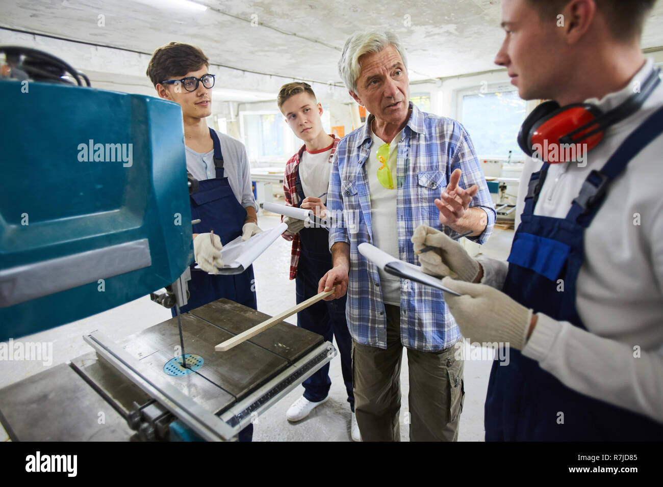 Carpenter explaining how to works with drilling machine Stock Photo