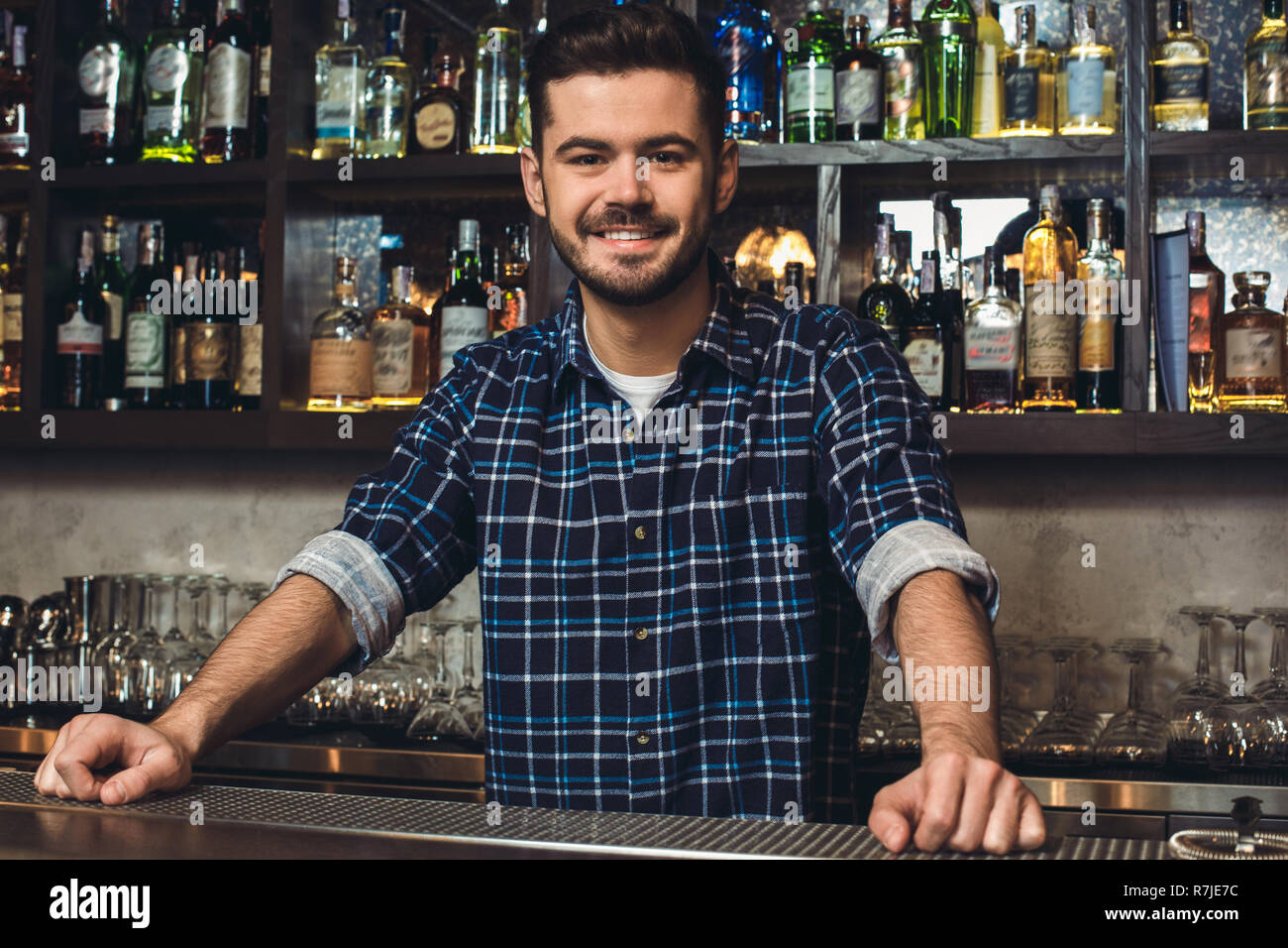 Young bartender standing at bar counter smiling confident Stock Photo