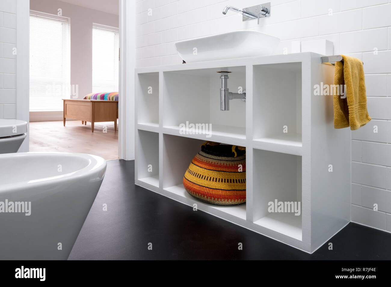 Contemporary white painted MDF bathroom unit, with colourful African bolga basket and black
