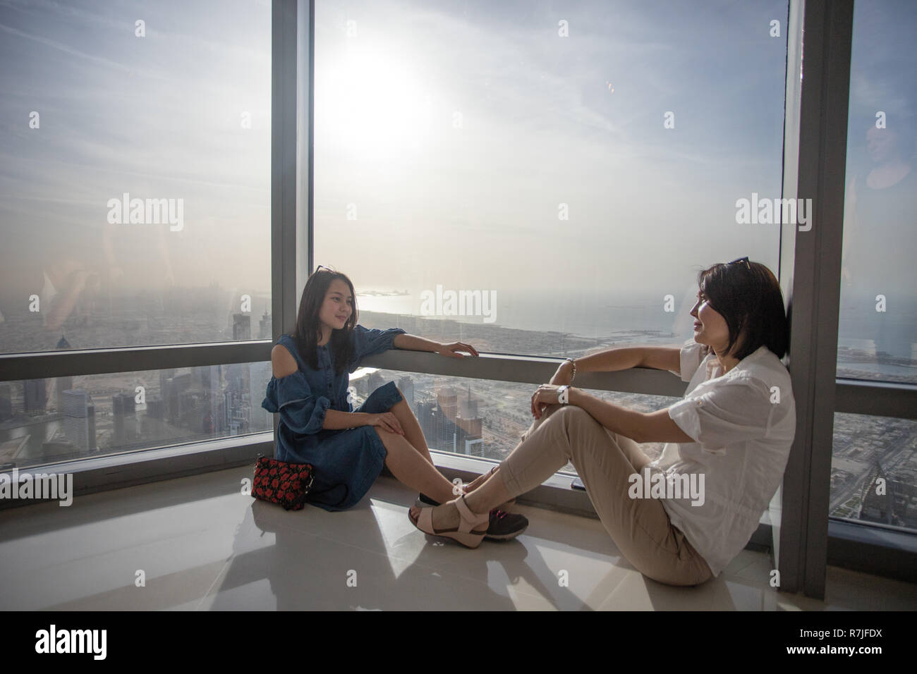 Two asian female tourists in the world record holding Burj Khalia skyscraper in Dubai, United Arab Emirates. Stock Photo