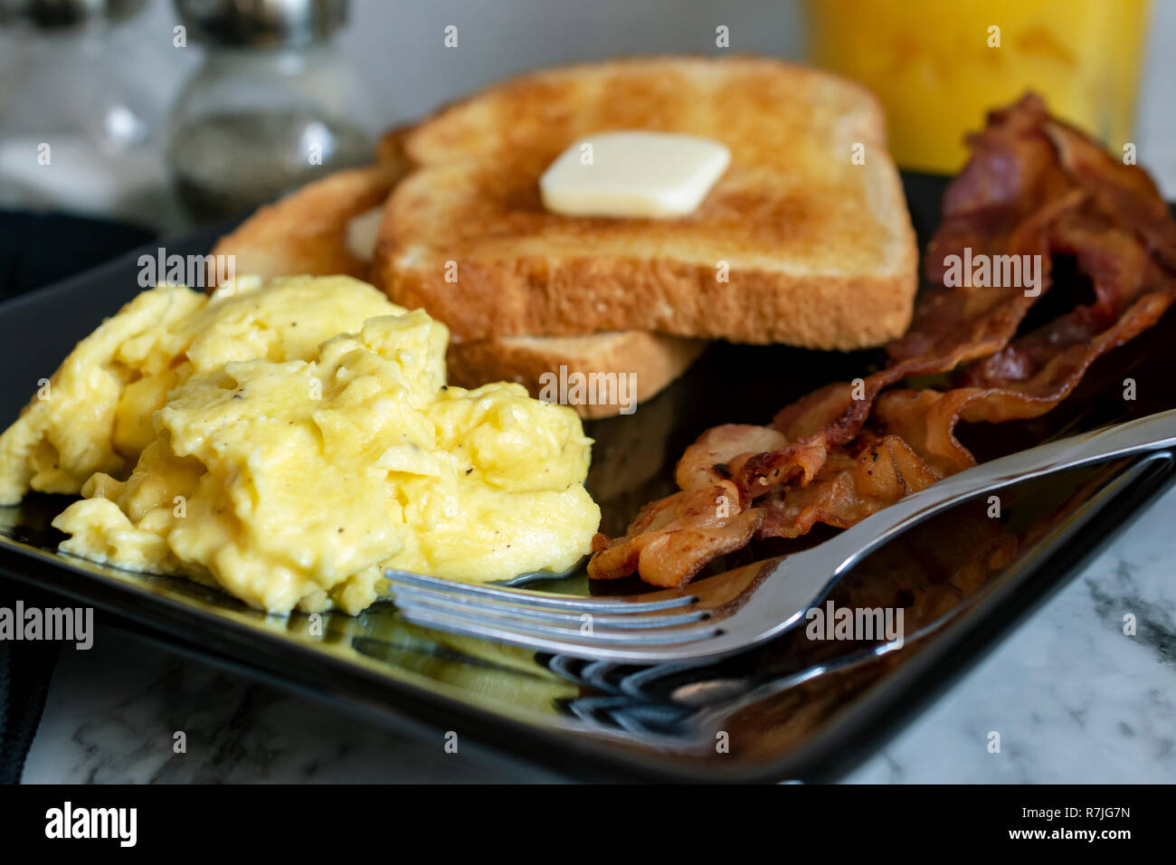 Scrambled Eggs Bacon And Toast On Black Plate With Fork Ready To Eat Stock Photo Alamy