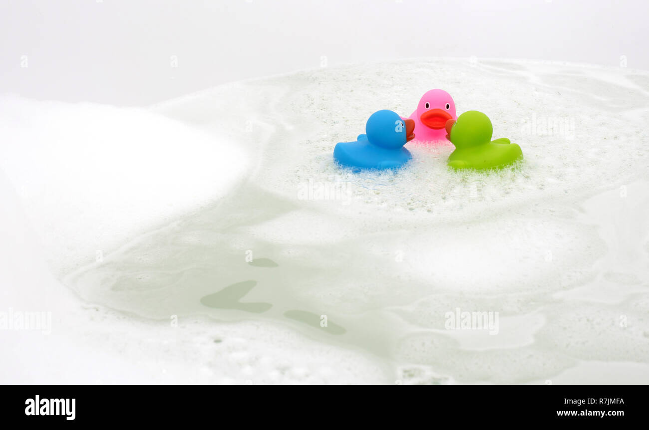 Pink, green and blue duck in a bathtub, surrounded by soap Stock Photo ...