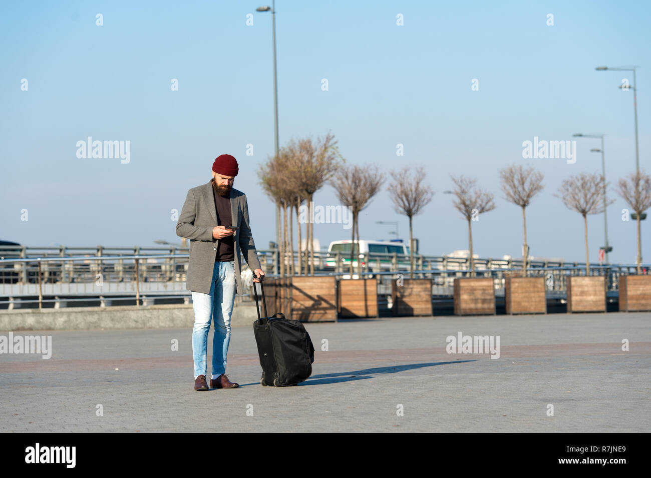 Moving to new city alone. Man bearded hipster travel with luggage bag on  wheels. Traveler with suitcase arrive airport railway station urban  background. Hipster ready enjoy travel. Carry travel bag Stock Photo -