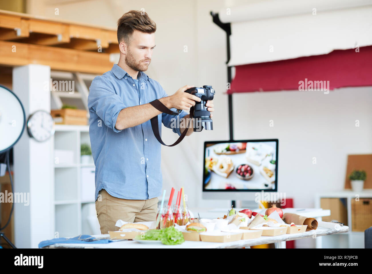 Portrait of handsome photographer taking photos of food while working in studio, copy space Stock Photo