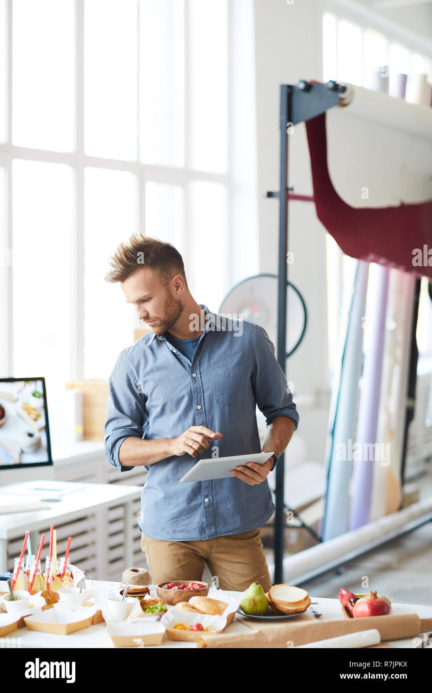 Portrait of handsome photographer using digital tablet while preparing set in studio Stock Photo
