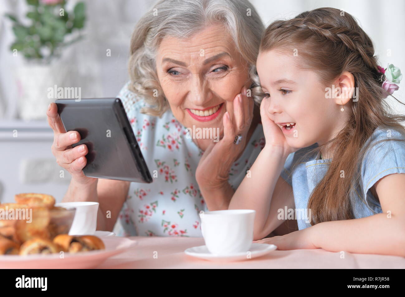 Cute little girl with her grandmother looking at tablet Stock Photo - Alamy
