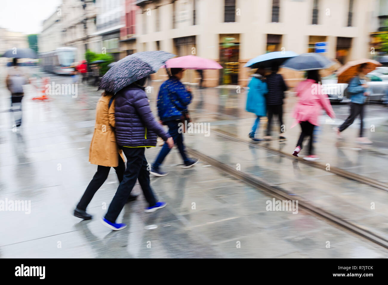 picture with camera made motion blur of people with umbrellas walking ...