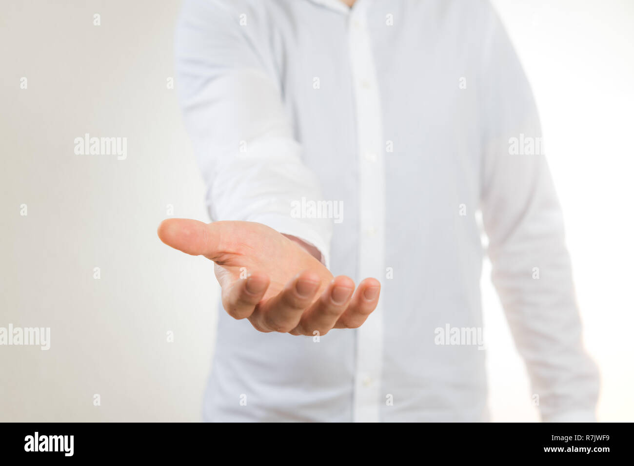 man with white shirt stretching out empty hand against white background Stock Photo
