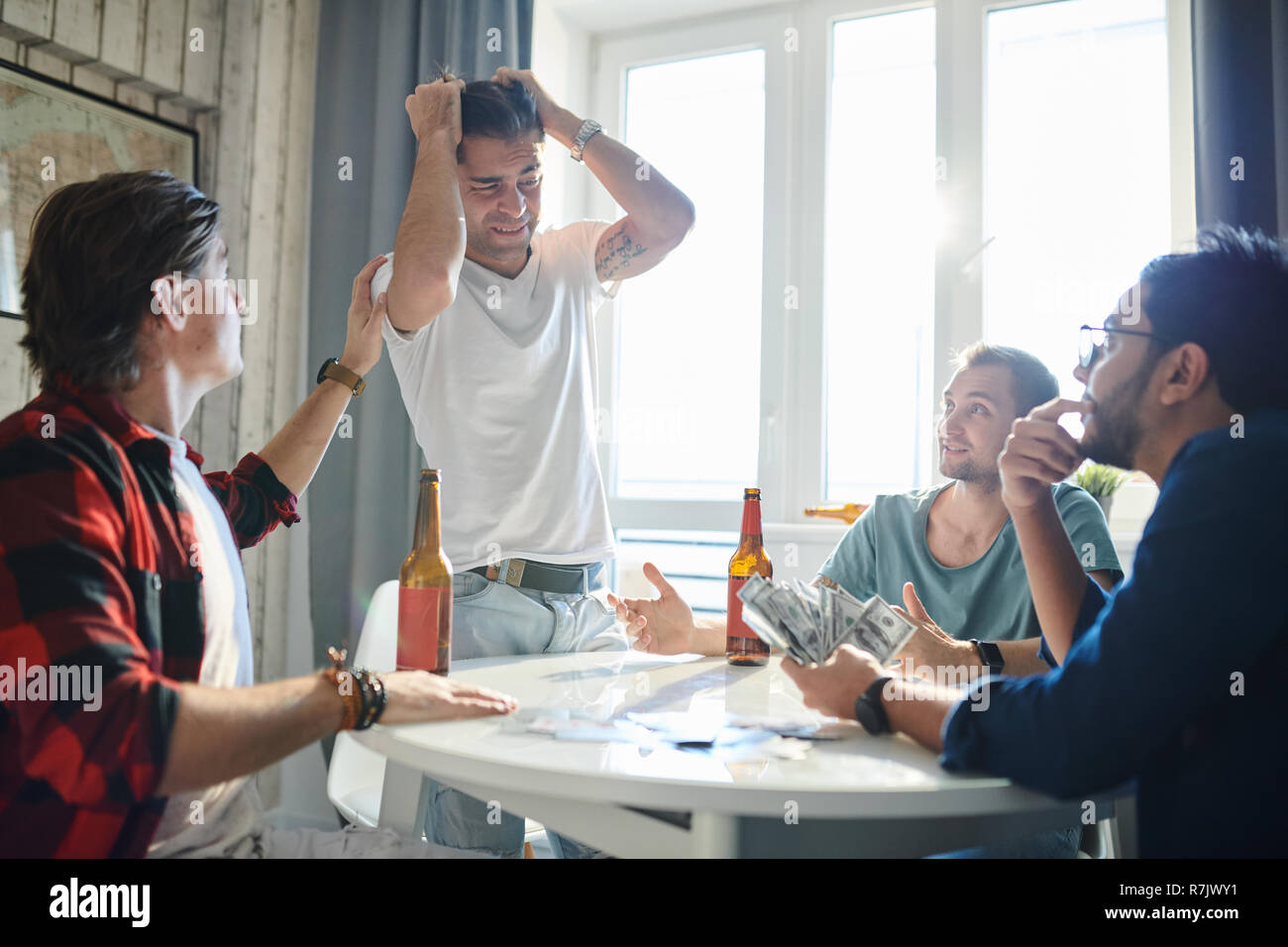 Upset young man lost in poker and didn't get his win with his friends  comfort him at the table at home Stock Photo - Alamy